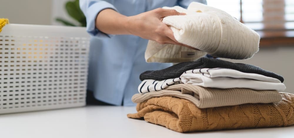 A woman ironing a shirt on an ironing board.